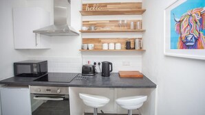 A compact kitchen with a microwave, toaster, coffee maker, and a 'hello' sign on the wall. - Beautiful Flat in Great West end Location (Glasgow City)