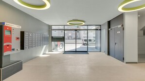 Un hall d’entrée moderne doté d’un distributeur automatique KASSEN, d’une entrée avec porte vitrée et d’un espace de stationnement visible à travers le verre.
