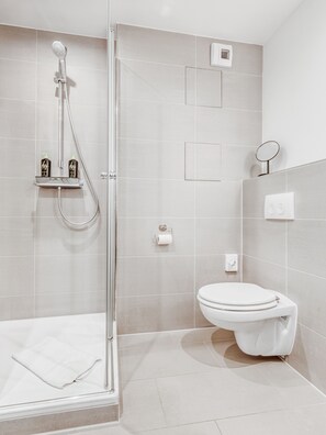 Ein modernes Badezimmer mit einer Duschkabine, Toilette und Handtuchhalter.