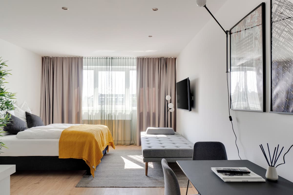 Une chambre d’hôtel moderne équipée d’un lit, d’un canapé, d’un bureau et d’une télévision.