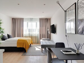 Een moderne hotelkamer met een bed, een bank, een bureau en een televisie.