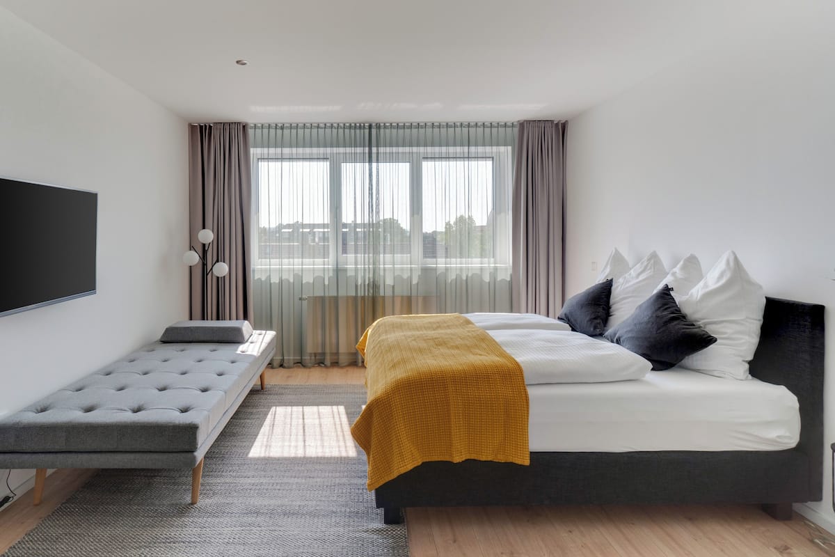 Une chambre à coucher moderne avec un lit, une table de chevet et un téléviseur fixé au mur.