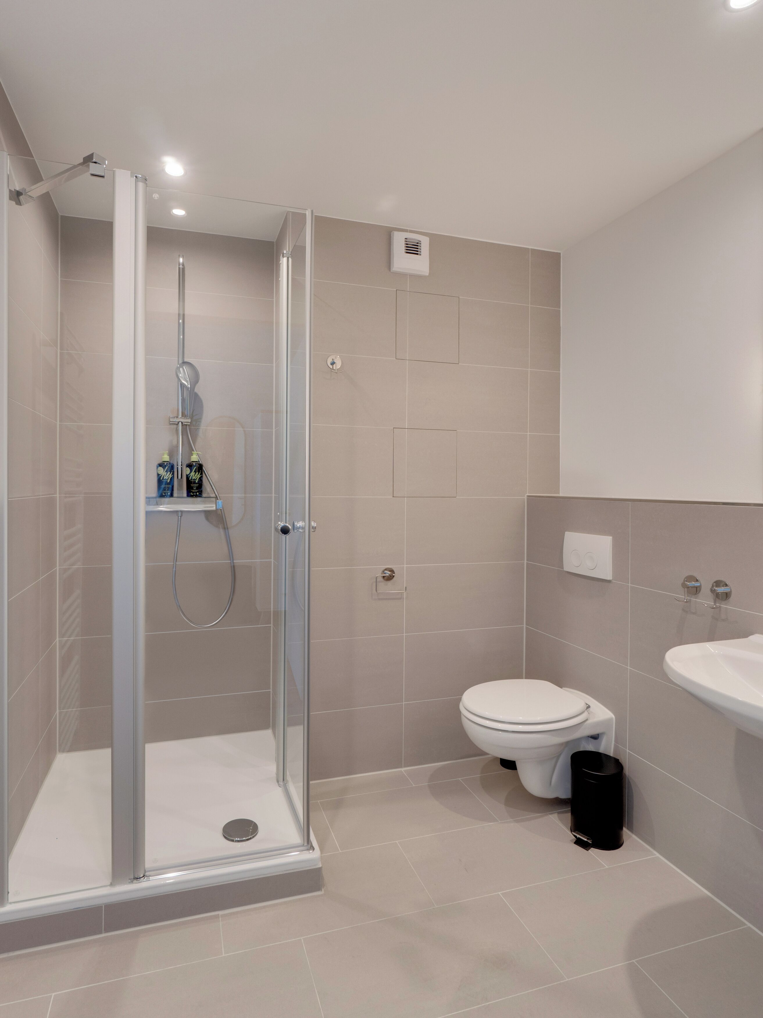 A modern bathroom with a glass-enclosed shower, a toilet, and a sink.