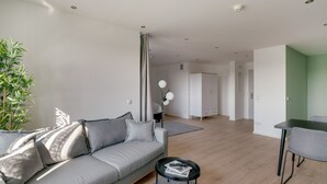 Un salon moderne avec un canapé gris, une petite table basse noire et un mur d’accent vert.