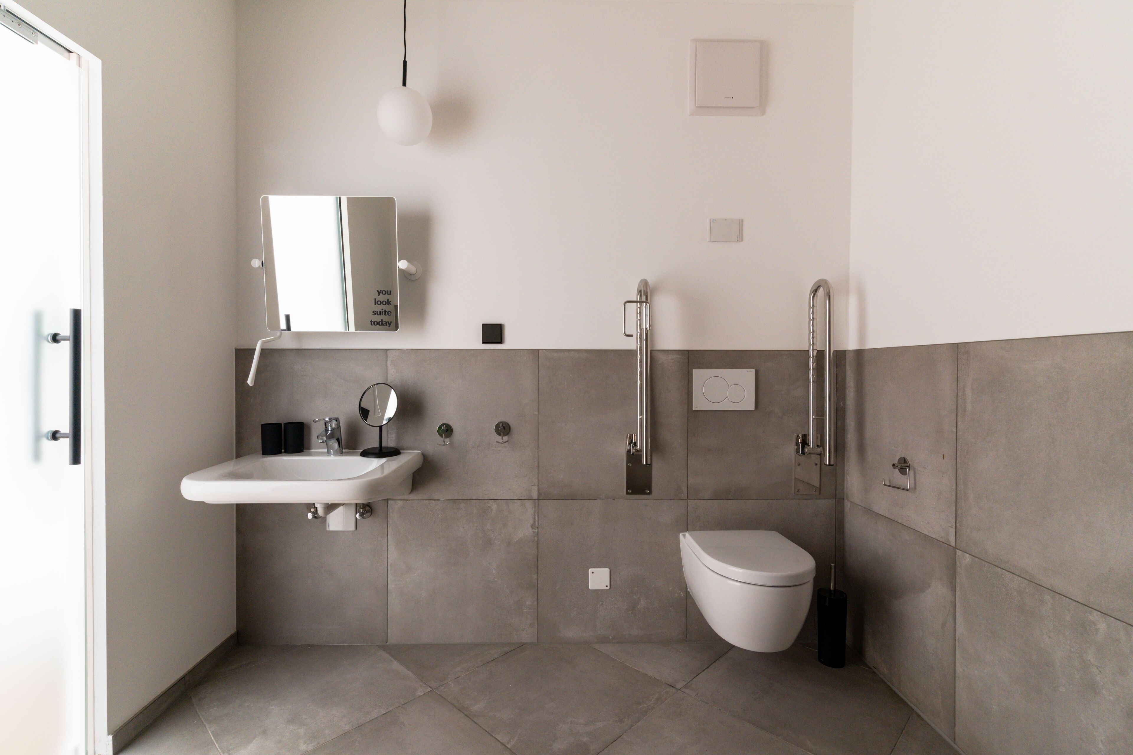 Une salle de bain moderne équipée d’un lavabo, d’un miroir, de toilettes et d’une douche.
