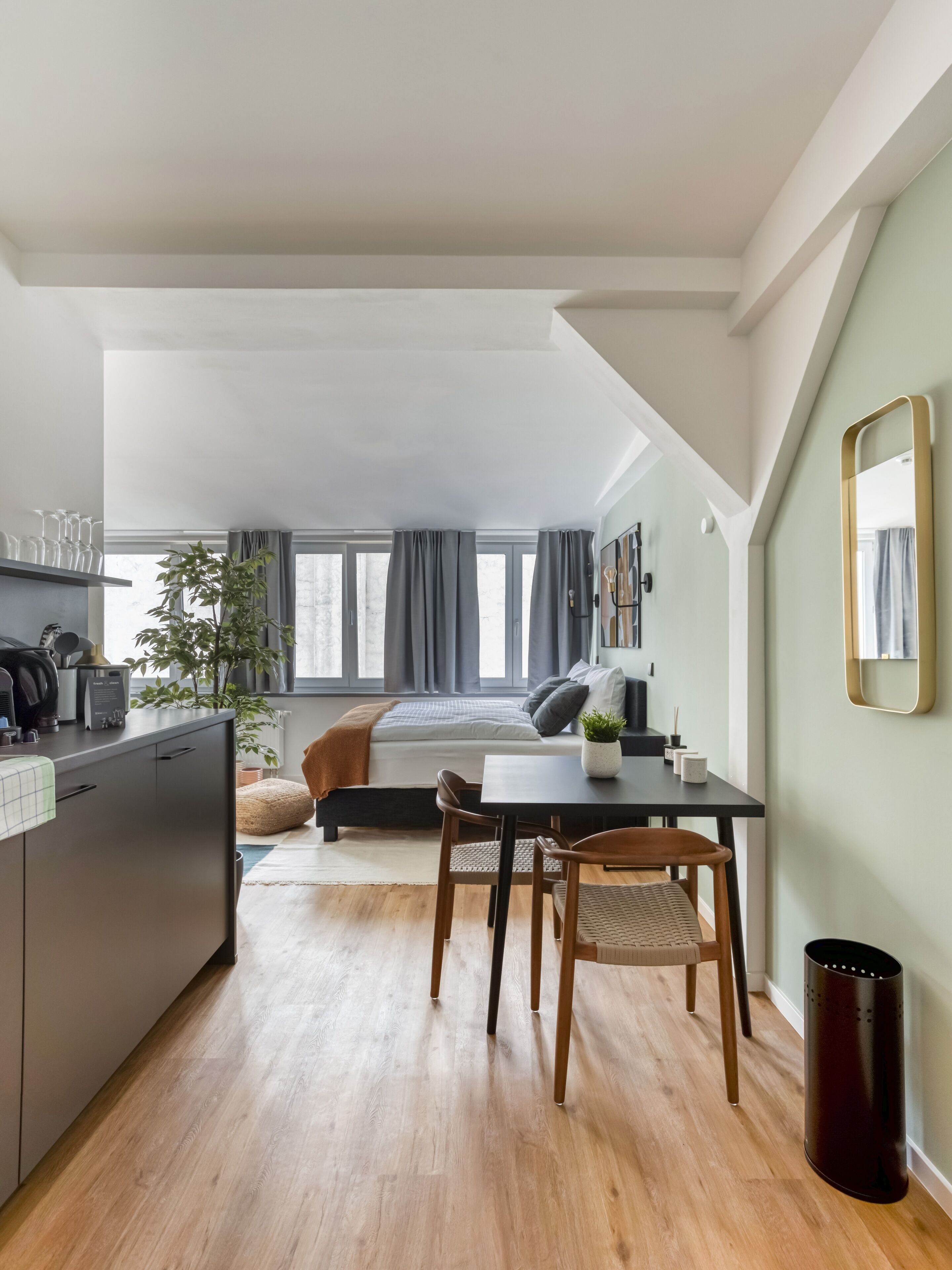 A modern, compact living space with a kitchenette, a dining area, and a bedroom.