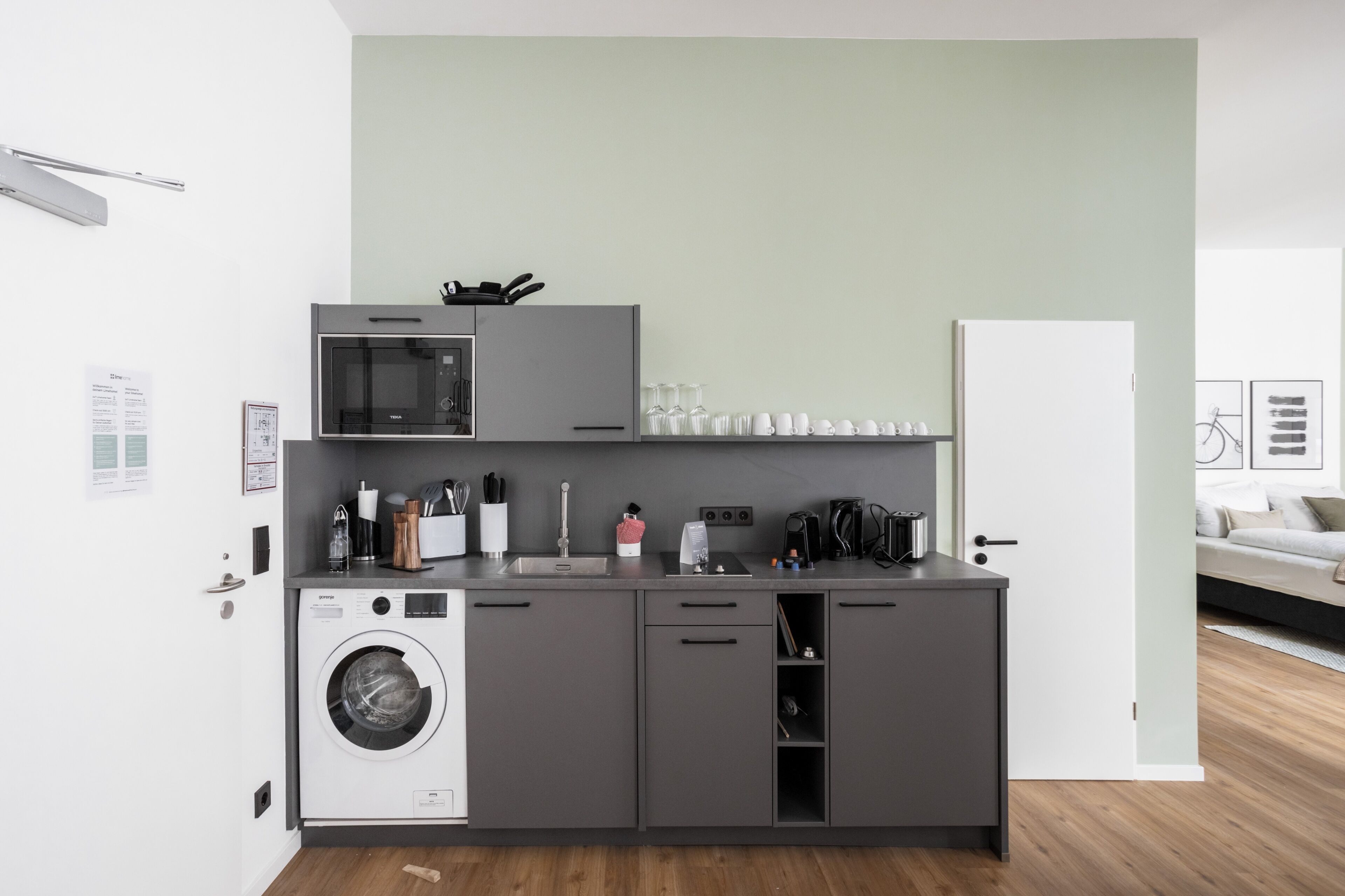 Una cocina compacta con lavadora, microondas y cafetera.