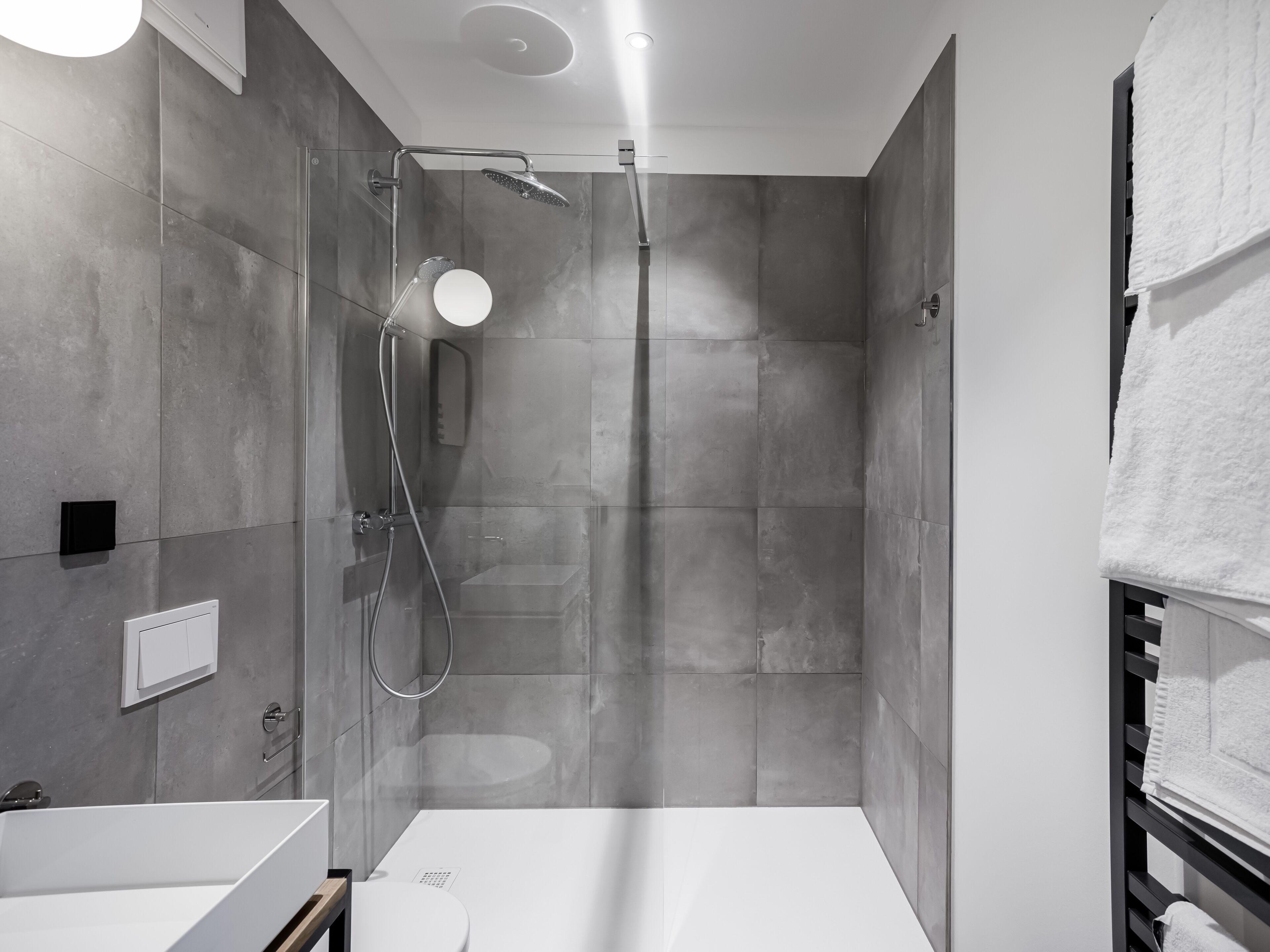 A modern bathroom with a glass-enclosed shower, a white sink, and a towel rack.