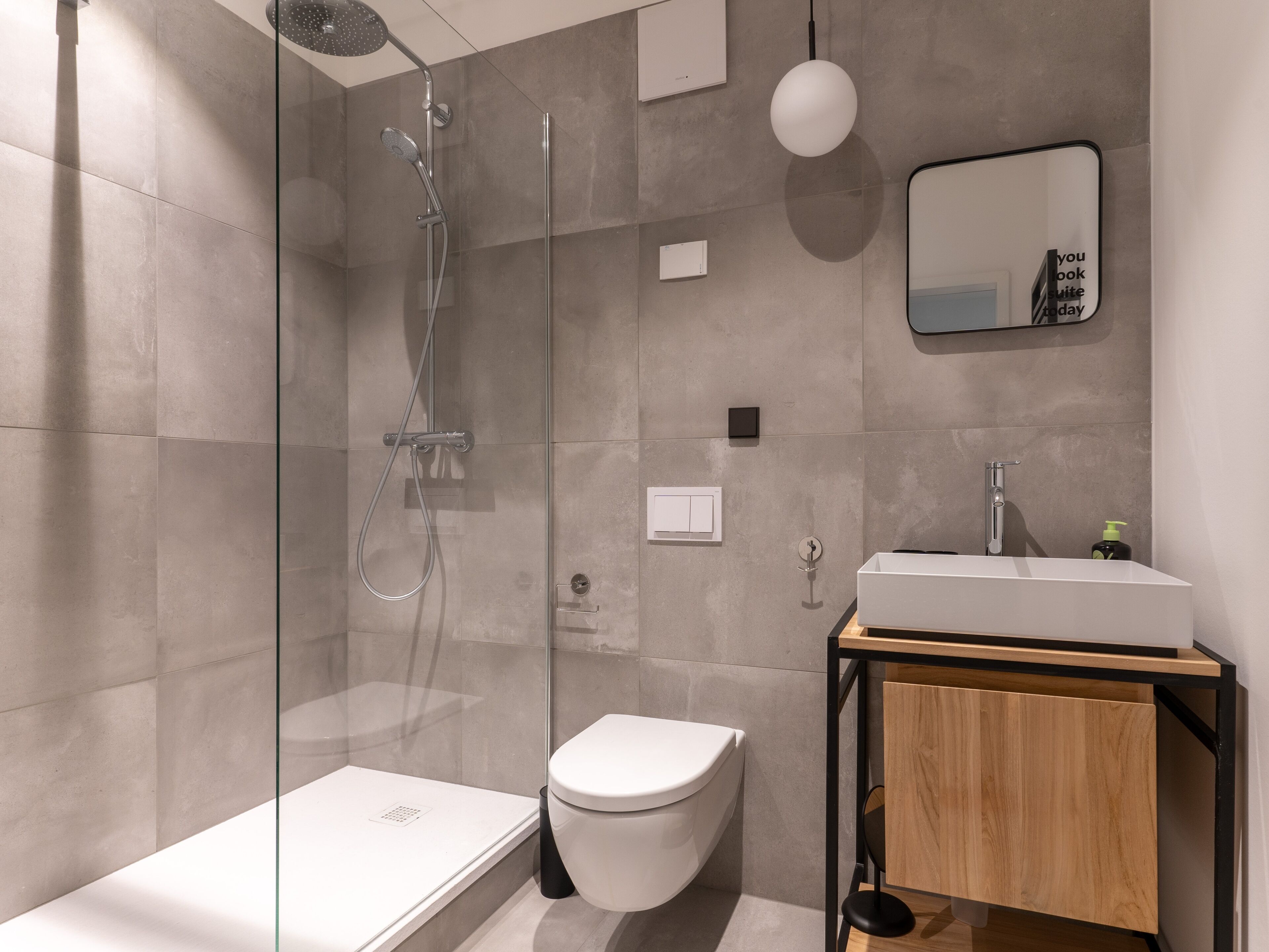 A modern bathroom with a glass-enclosed shower, a white toilet, and a wooden vanity with a mirror.