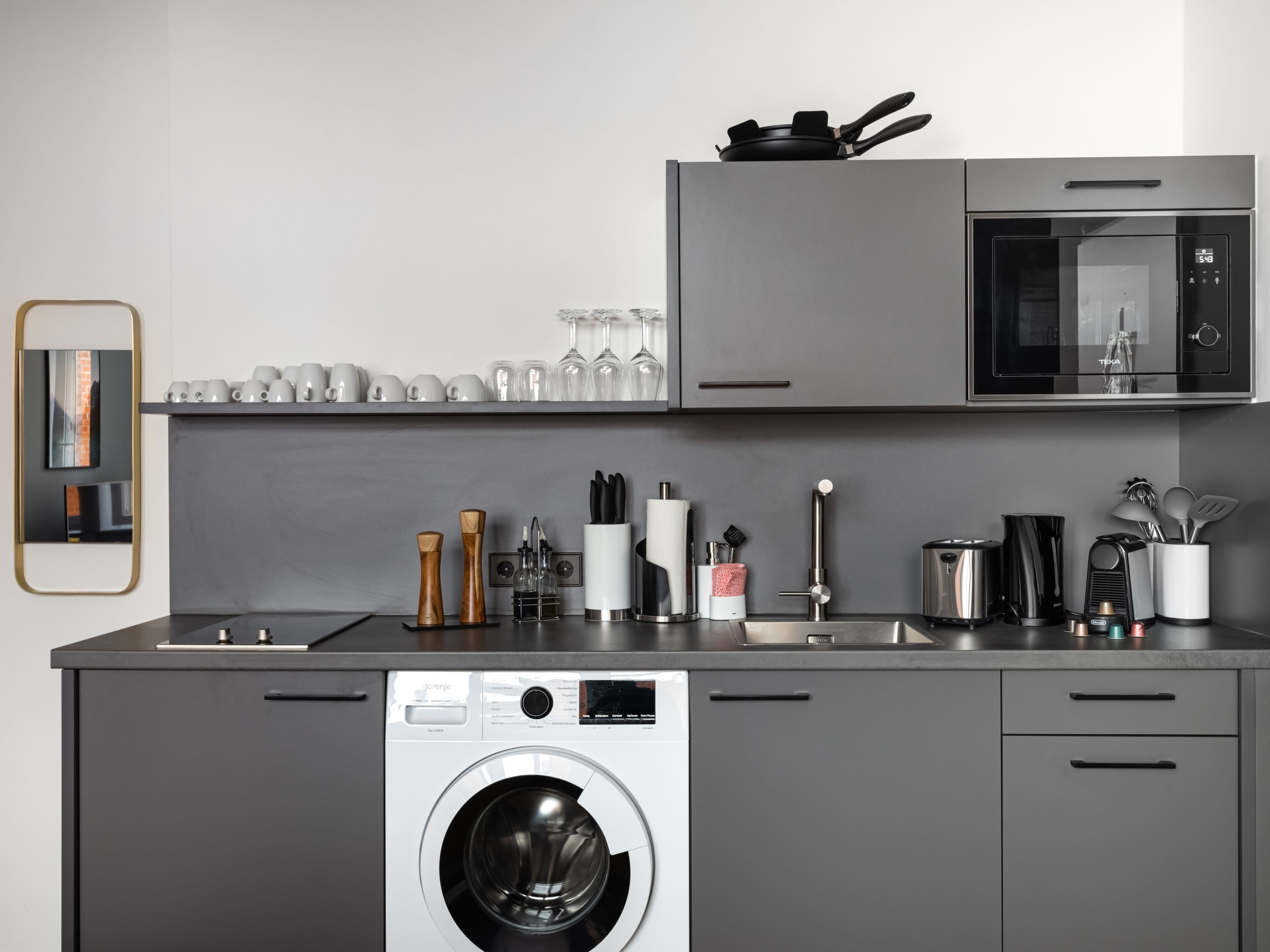 A modern kitchen with a built-in washer, microwave, and oven.