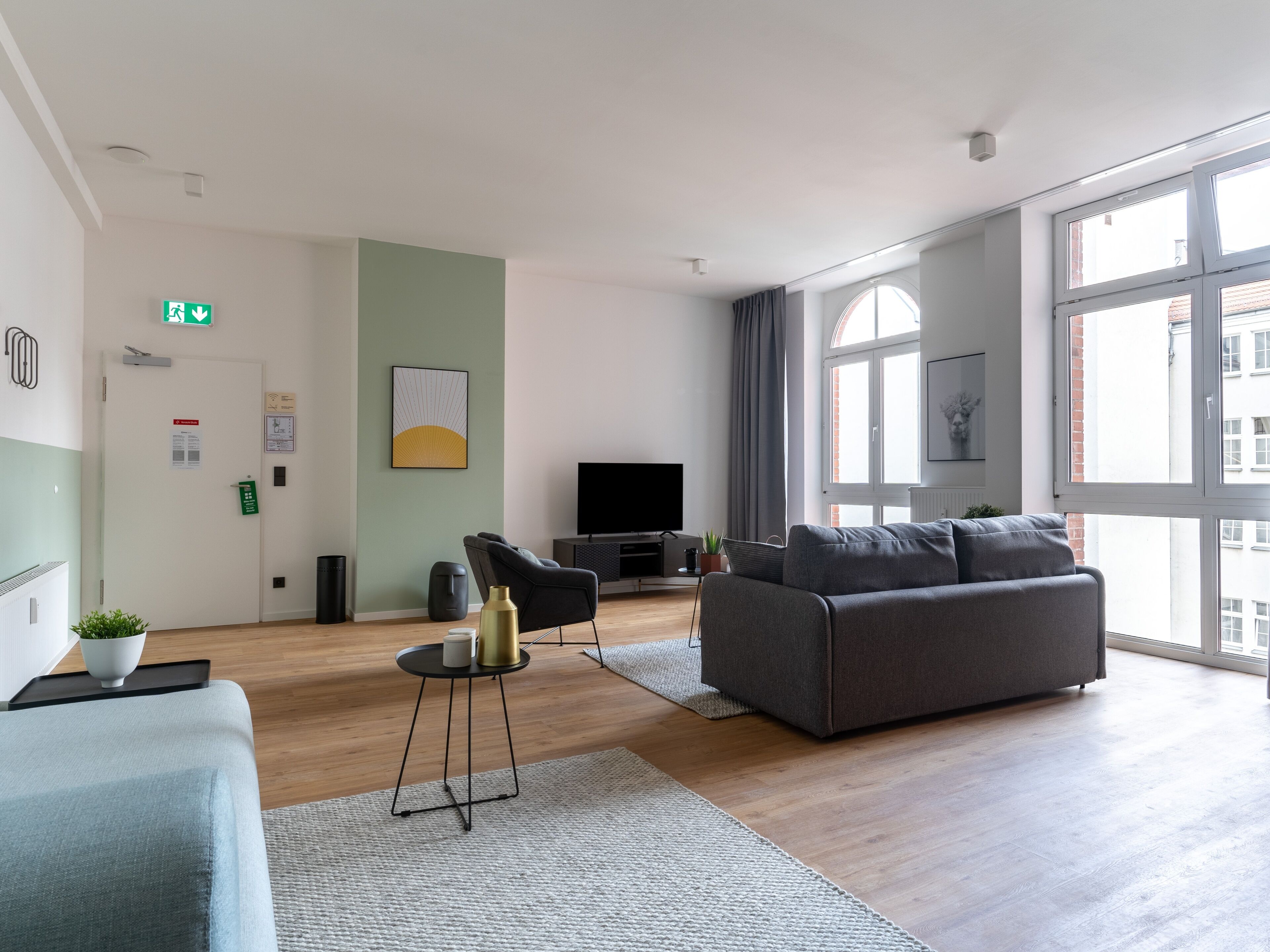 A modern living room with a grey sofa, a television, and a large window.