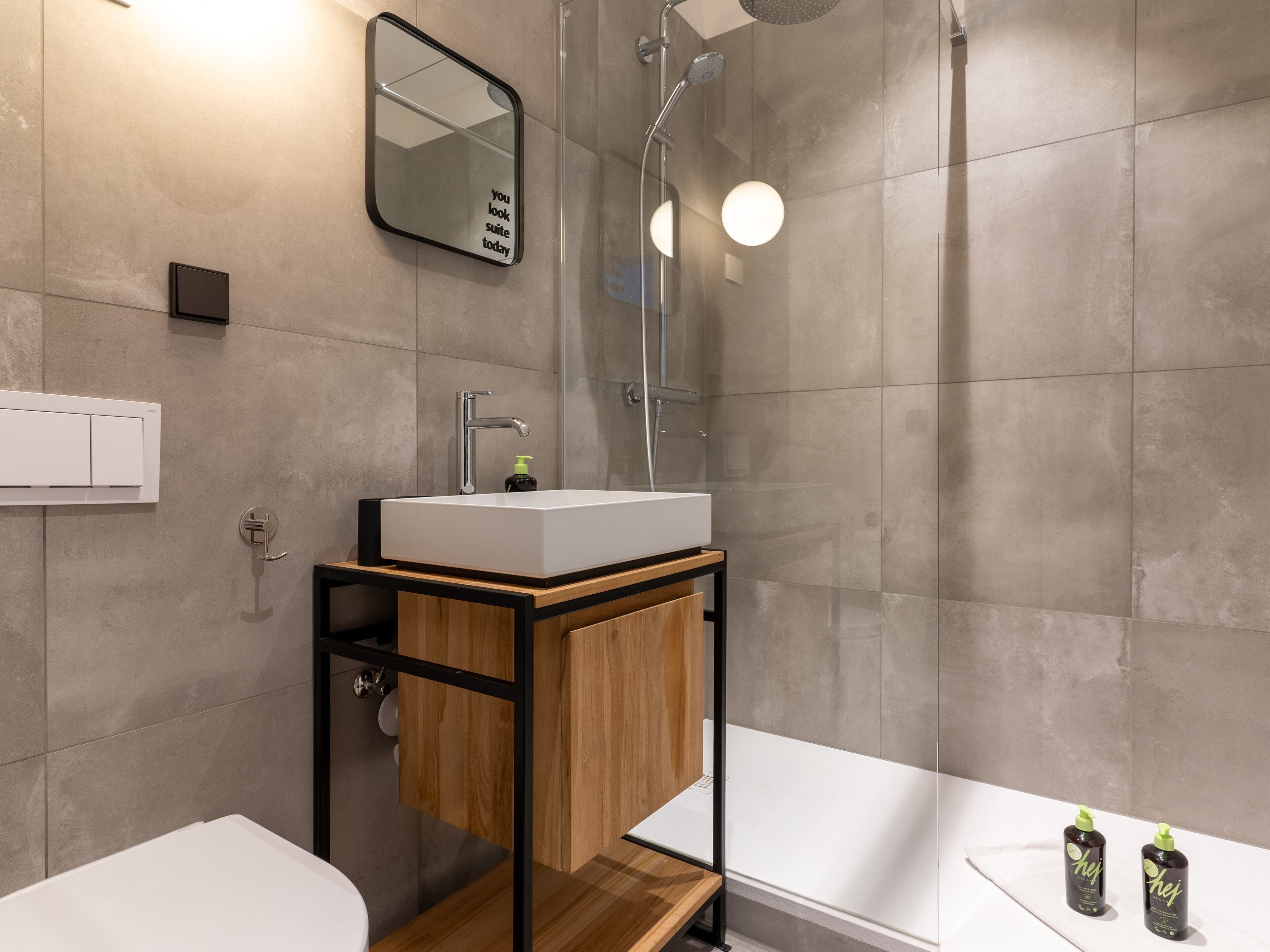 Un baño moderno con un lavamanos blanco, un espejo y una ducha.