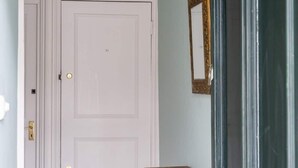 Een hal met een witte deur, een houten plank en een hanglamp.