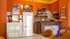 Una zona de bar con mostrador de madera, una lámpara de araña y cuadros en la pared.