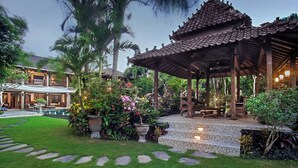 A traditional wooden gazebo with a tiled roof, surrounded by lush tropical plants and a well-maintained lawn. - Villa Avalon (Canggu)