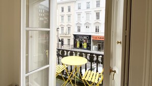 A room with a large window, a yellow table, and a patterned chair. - Stylish Apartments in Pimlico (London)
