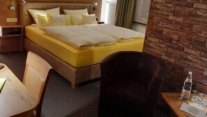 A hotel room with a bed, a desk, a chair, and a wooden wall.