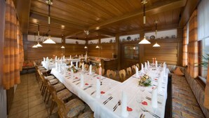 A long dining table set with candles, white tablecloths, and chairs in a wooden interior.