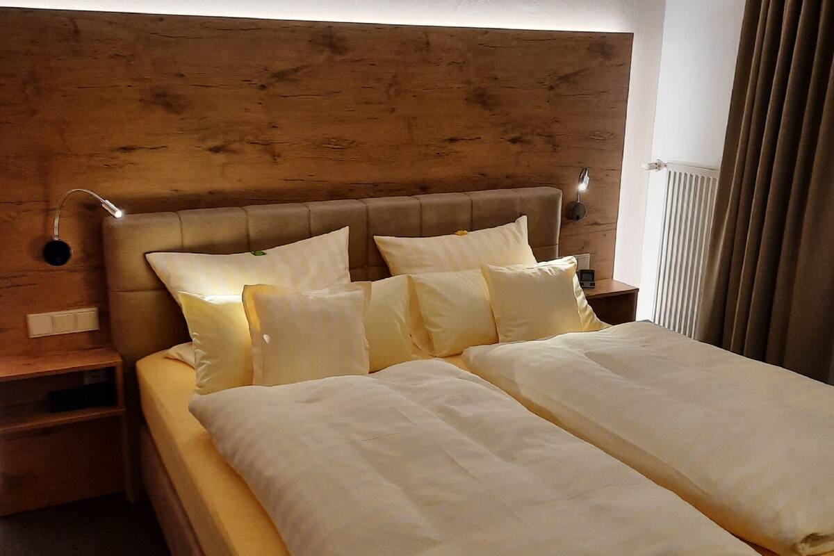 Un lit bien fait, avec des draps blancs et une tête de lit en bois.