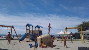 Uma praia com parquinho, incluindo escorregadores e estruturas para escalar.