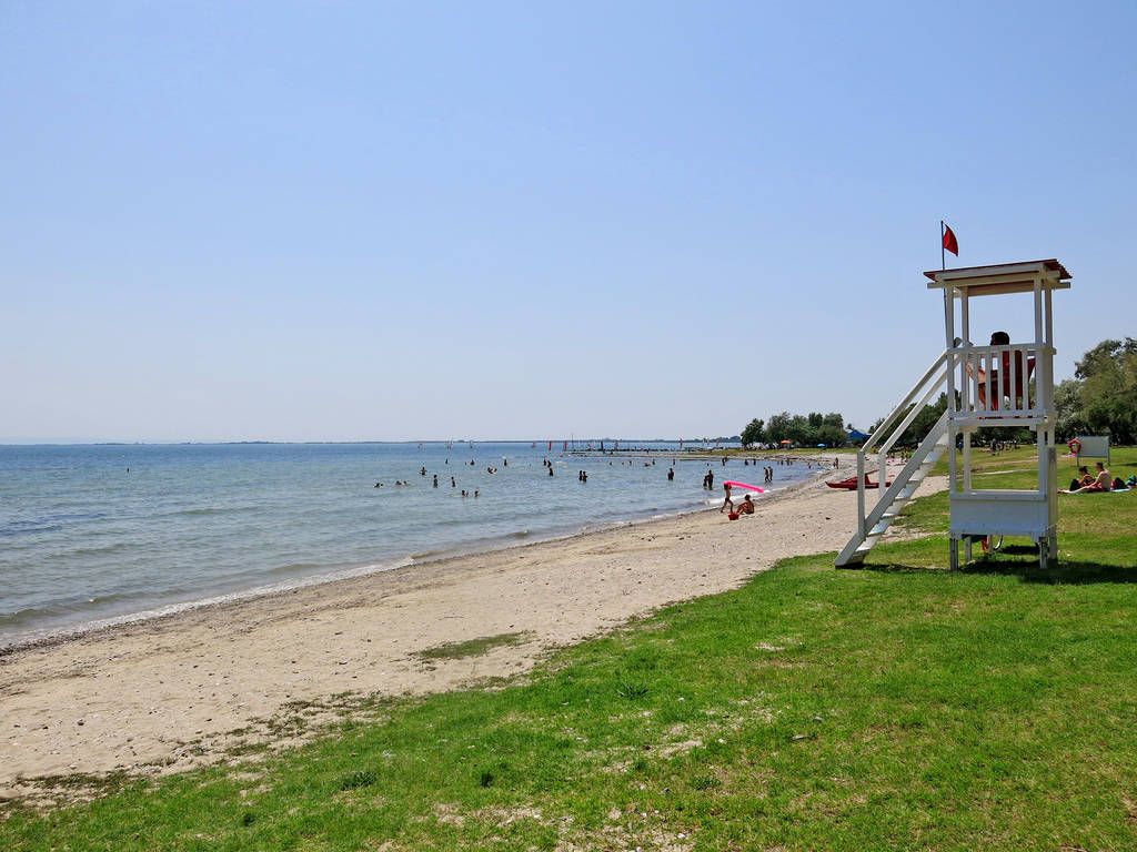 A beach with a lifeguard tower, a clear sky, and a distant bridge.