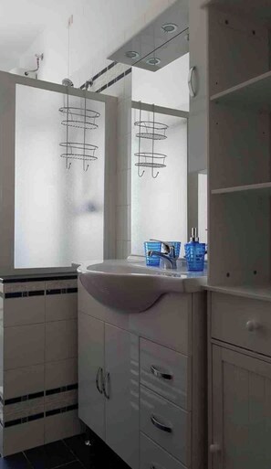 Features a large mirror above a sink, two towel racks, and a cabinet with drawers.