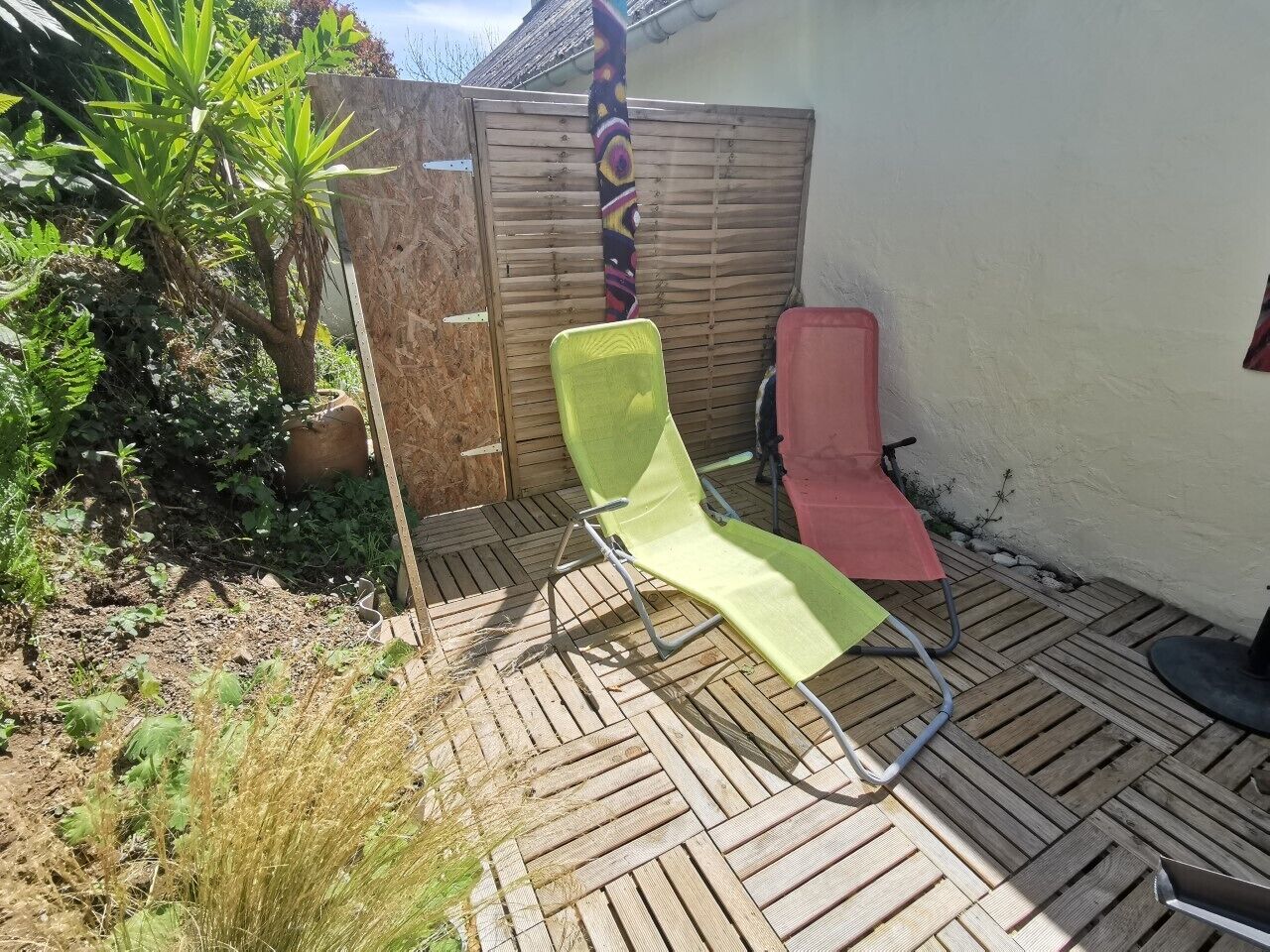 Un patio con dos sillones, una cerca de madera y una planta en maceta.