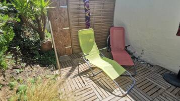 Un patio con dos sillones, una cerca de madera y una planta en maceta.