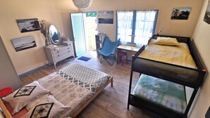 Une chambre avec deux lits, un bureau, une chaise, une commode et une fenêtre avec des rideaux.