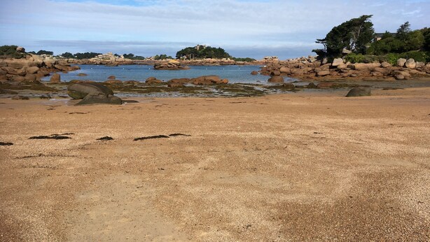 Une plage avec de gros rochers et une eau calme.