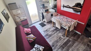 Un espace de vie compact comprenant un coin repas, une kitchenette et un mur d’accent de couleur rouge.