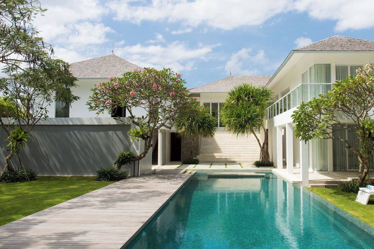 A modern house with a swimming pool, a wooden deck, and a well-maintained garden.