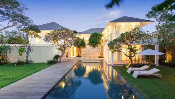 Uma casa moderna com piscina, um deck de madeira e um gramado bem cuidado.