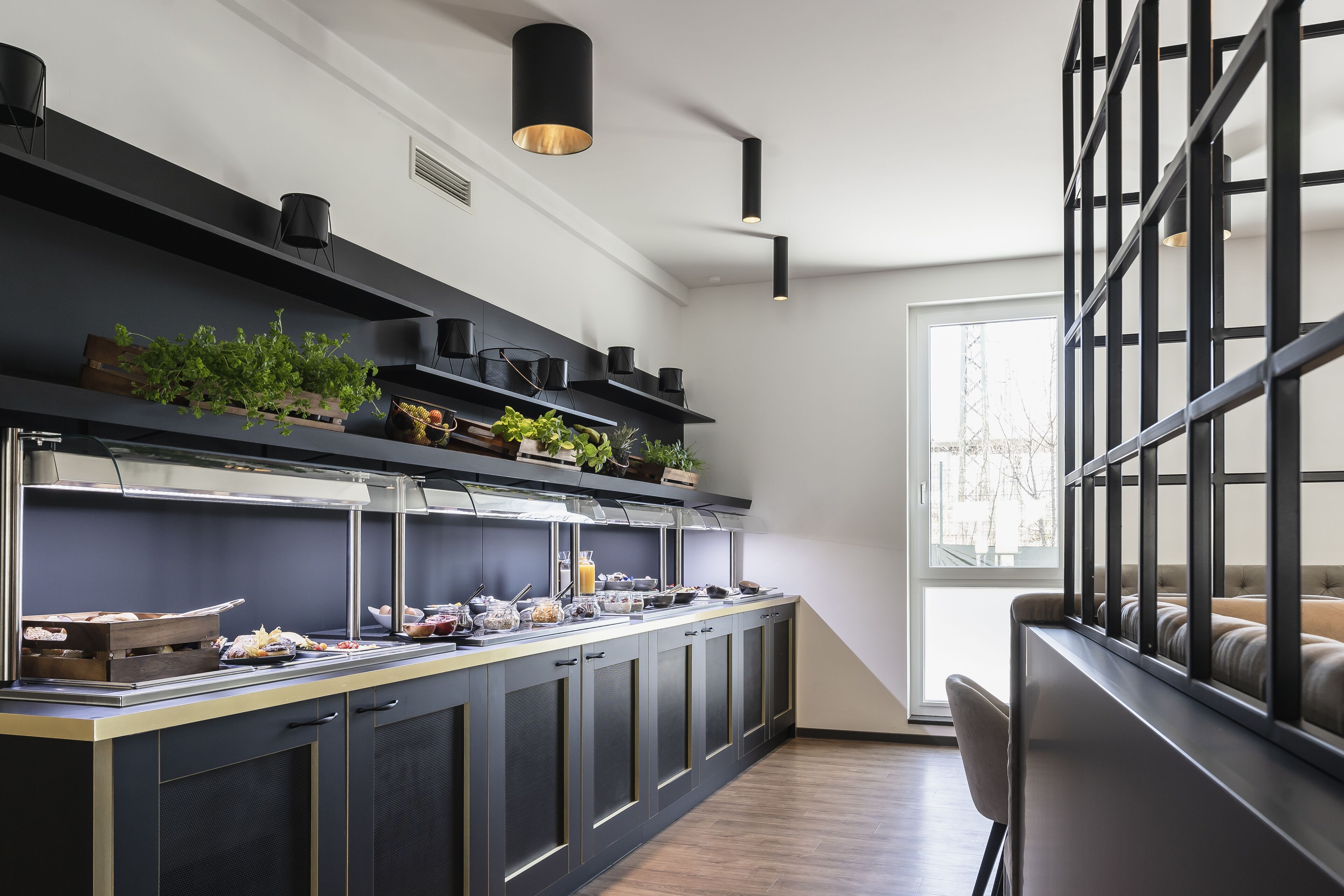A modern kitchen with a built-in counter, black cabinets, and a window providing natural light.