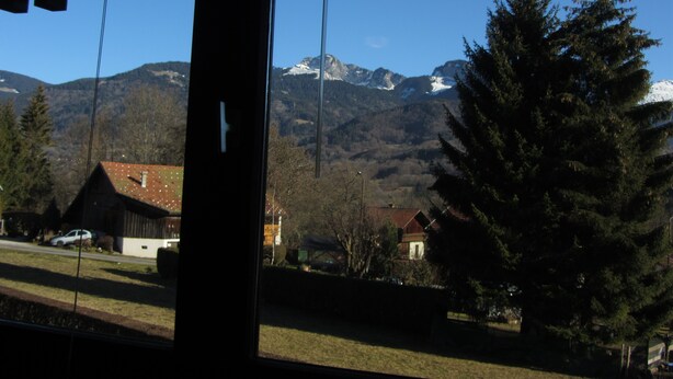 A view through a window of a building with a mountain landscape in the background.
