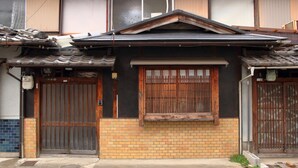 A traditional Japanese house with a tiled roof, wooden doors, and a brick base. - Kyo Maimai (Kyoto)