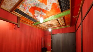 A room with red walls, a round table, and a ceiling with floral patterns. - Kyo Maimai (Kyoto)