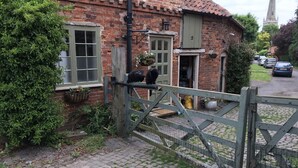 A brick house with a green gate, a window, and a door.