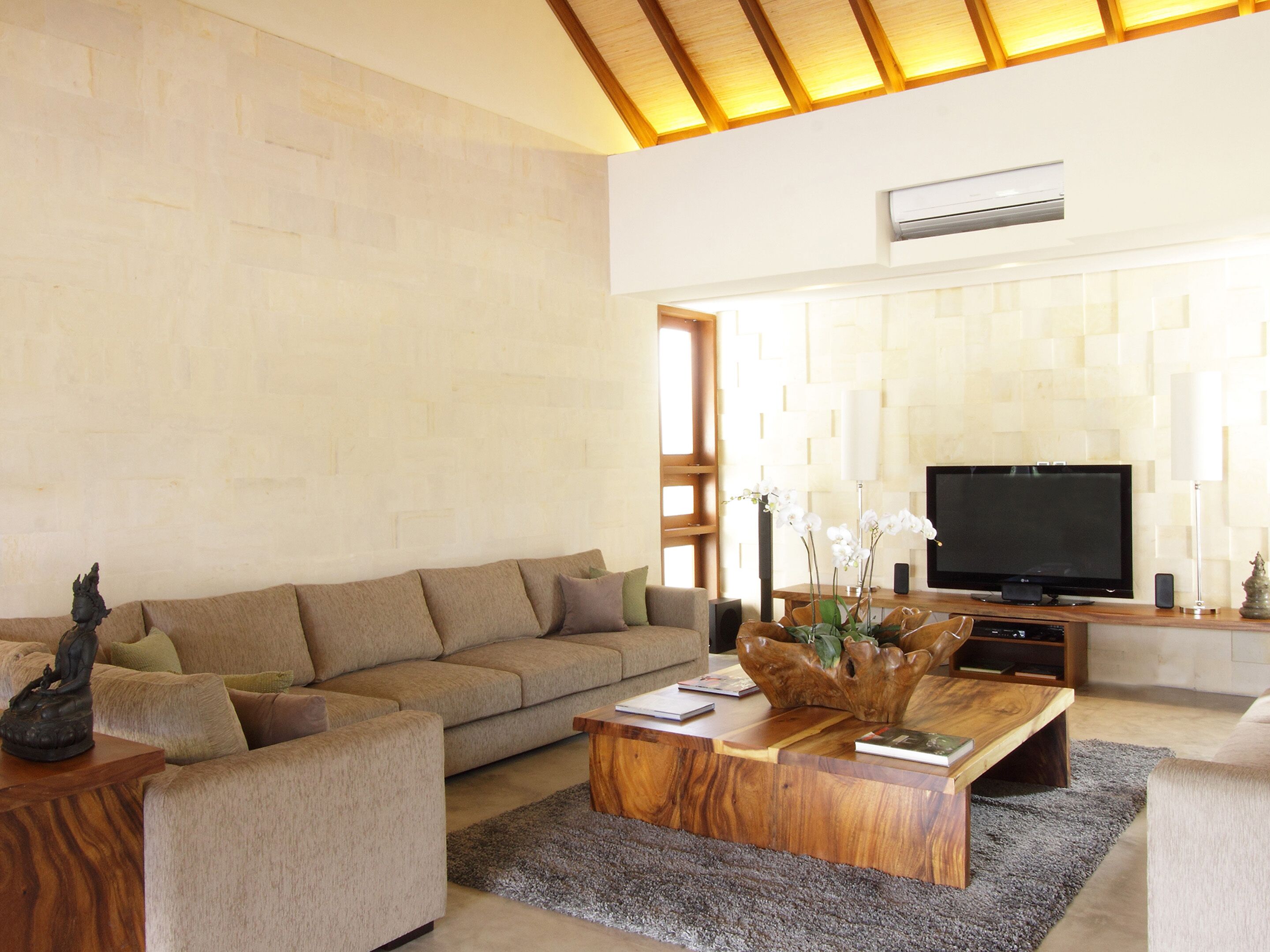 Una sala de estar moderna con un sofá color beige, una mesa de centro de madera y un televisor de pantalla plana.