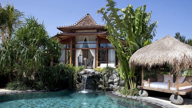 A resort with a clear pool, a waterfall, and a traditional thatched-roof structure. - Dea Villas (Canggu)