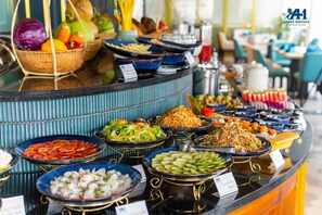 A buffet with various dishes including sliced tomatoes, cucumbers, and salads.