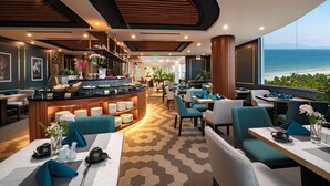 Un restaurant moderne doté d’un bar, de tables et d’une vue sur l’océan.
