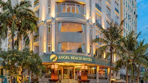 Un hôtel à plusieurs étages, doté d’une façade incurvée, de balcons à chaque étage et d’une entrée imposante sur laquelle est apposée une enseigne indiquant « Angel Beach Hotel ».