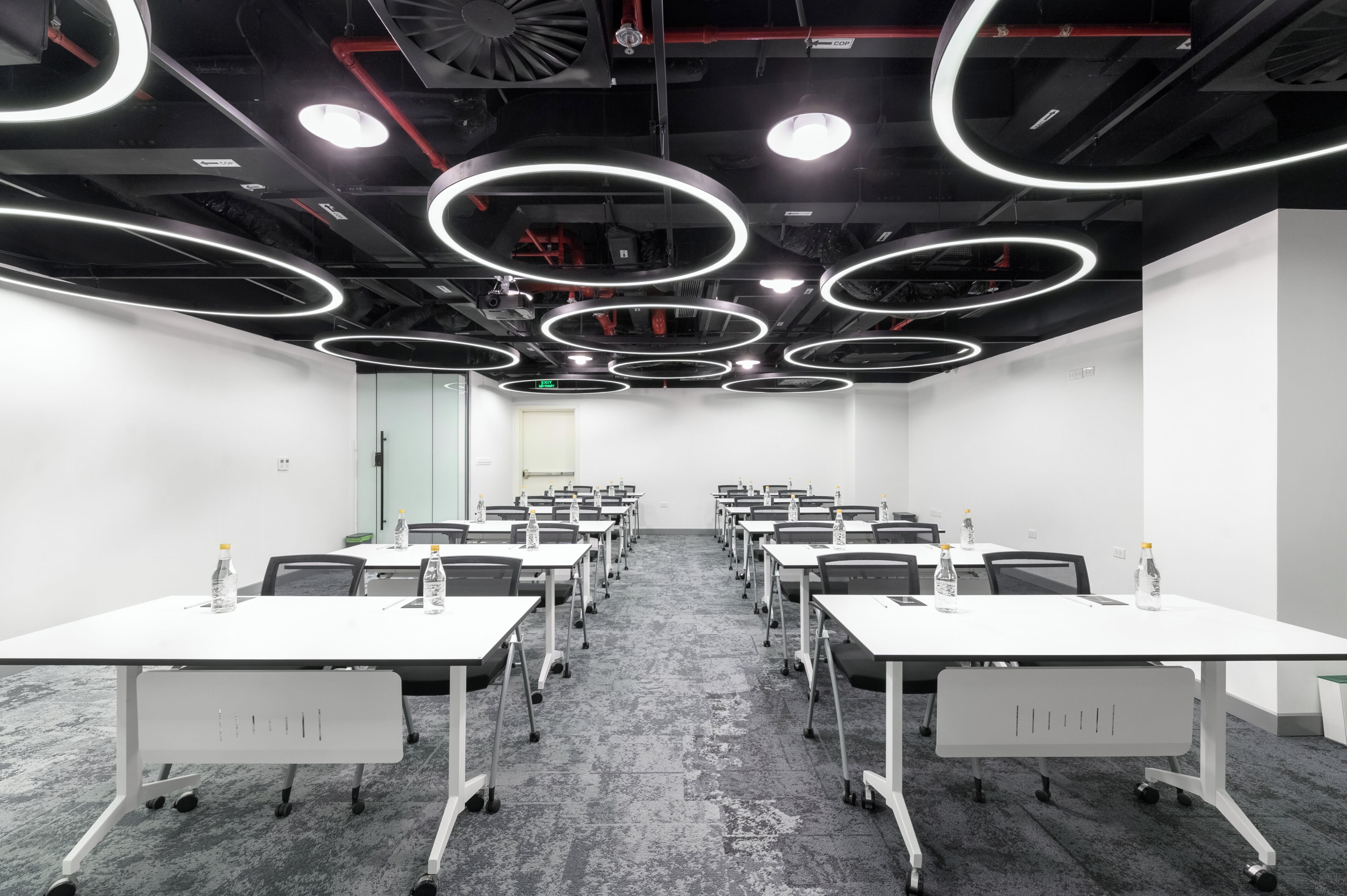 A conference room with white tables, chairs, and a carpeted floor.