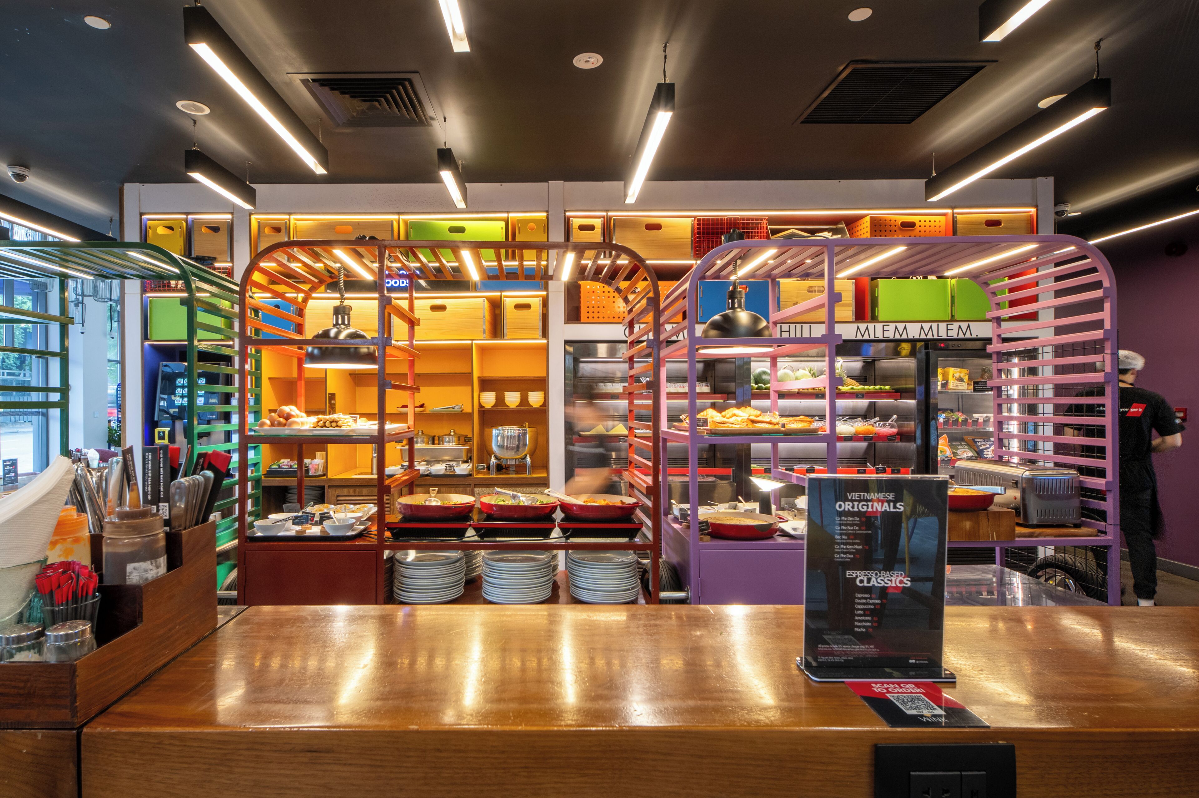 L’intérieur d’un restaurant, avec un comptoir, des étagères remplies de produits alimentaires et un présentoir à menus.