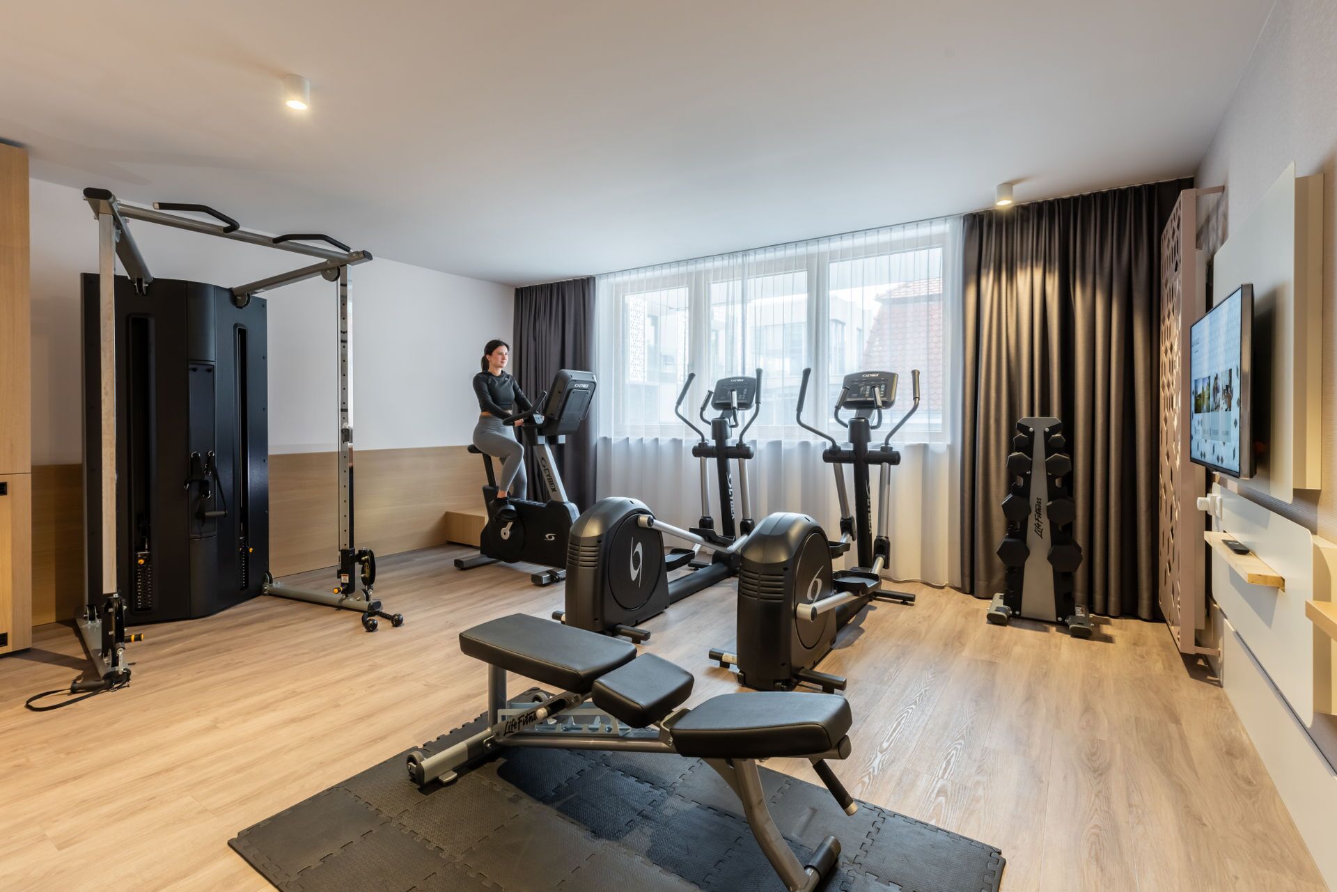 A modern gym with cardio machines, weightlifting equipment, and a large mirror.