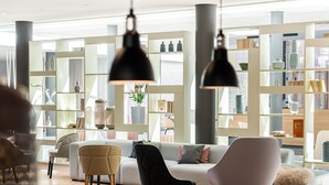 A modern living room with a sofa, chairs, and a bookshelf filled with decorative items.
