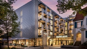A modern hotel with a patterned facade, multiple balconies, and a well-lit entrance.