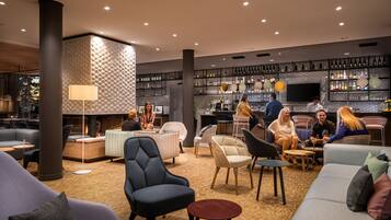 A modern lounge area with seating, a fireplace, and a bar with shelves of bottles.