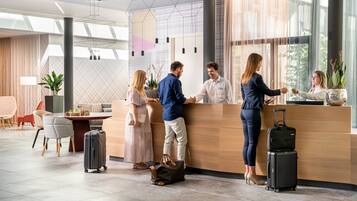 Un moderno vestíbulo de hotel con mostrador de recepción, zona de estar y amplias ventanas.